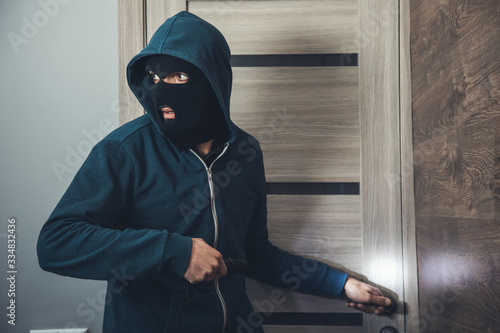 Canvas Print burglar sneaking into the house with flashlight