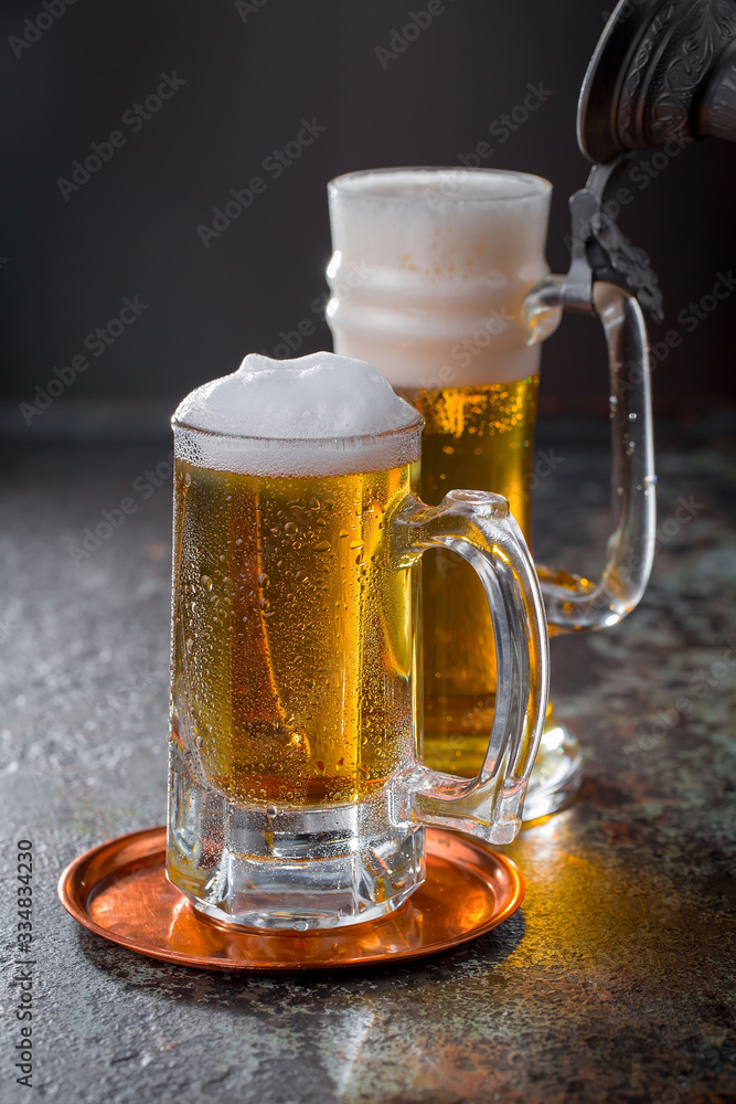 Light frothing beer in a glass, on an old background. Light frothing beer in a glass, on an old background.