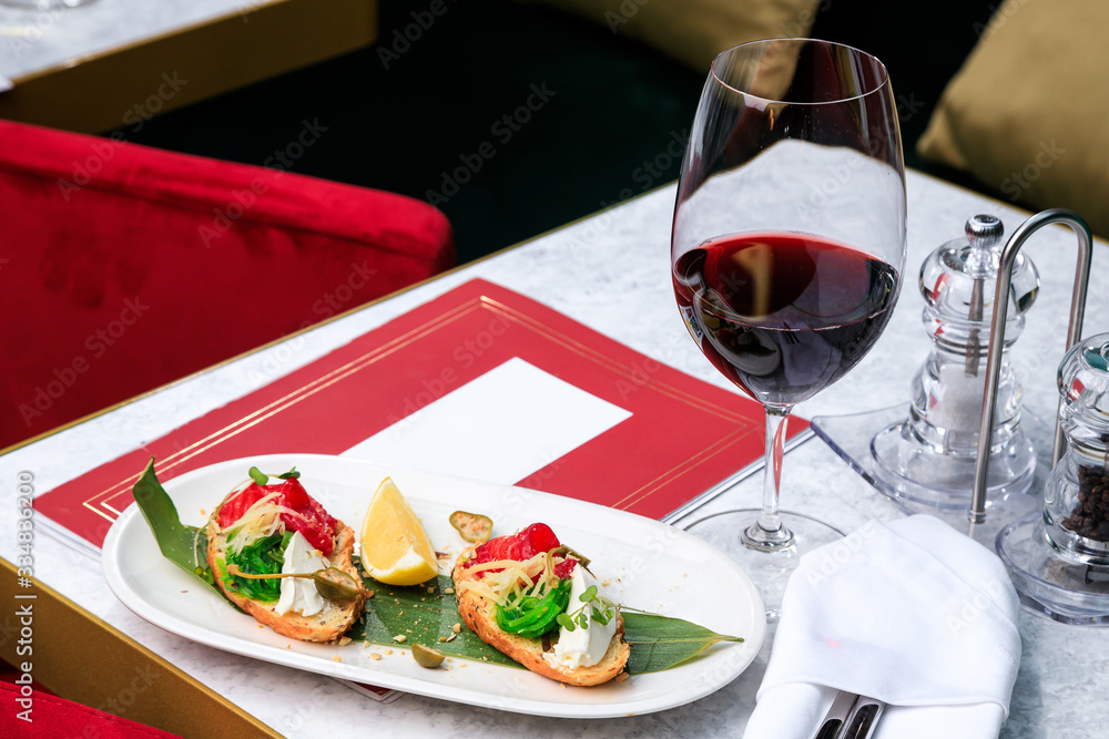 Crispy bruschetta with salmon, cheese, seaweed. Glass of red wine. Place for text