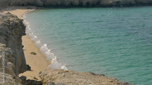 Aerial of tranquil sea waters hitting on an exotic beautiful remote empty beach photo