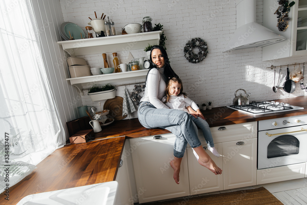Mom and Little Daughter cook in the kitchen and play. Family, happiness. Mom and Little Daughter cook in the kitchen and play. Family, happiness.