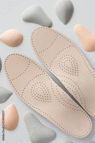 A pair of leather orthopedic insoles surrounded by components. Pelots for unloading the cross arch of different shapes and sizes. Choice.
