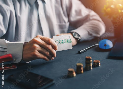 Businessman representing a credit card and has on the table a staircase of the economy with coins