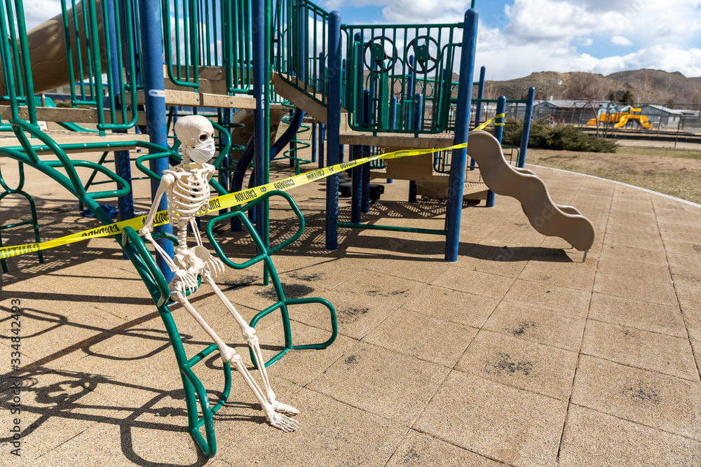 Adult skeleton sitting on playground equipment at an empty closed park on a nice day