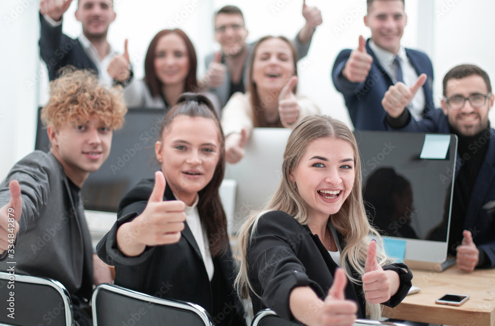 business team sitting at a Desk and showing thumbs up business team sitting at a Desk and showing thumbs up