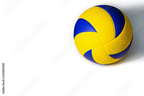 Closeup yellow blue volleyball sports equipment with light shining from the front, with shadow on the back, isolated leather volley ball object and copy space on a white background