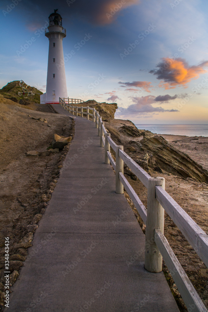 Panoramic scenic landscape view of the Castlepoint lighthouse in sunrise colours, white landmark, tourist popular attraction/destination in North Island, New Zealand. 