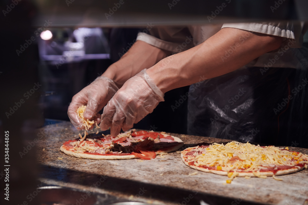 Man making pizza at the kitchen. Ingredients for Italian pizza. Gloved hands. Man making pizza at the kitchen. Ingredients for Italian pizza. Gloved hands.
