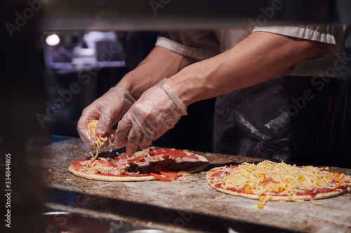 Man making pizza at the kitchen. Ingredients for Italian pizza. Gloved hands.