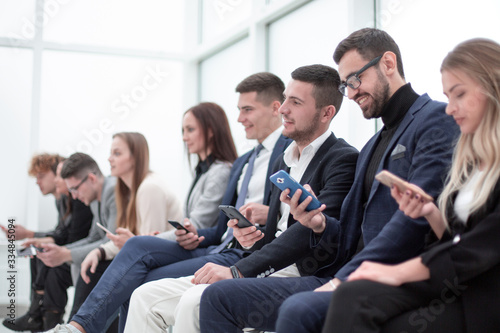 group of young business people with smartphones sitting in a row.