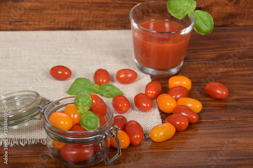 a glass jar full of red and yellow tomatoes and a glass of spicy tomato juice