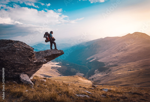 hiker with a big backpackon the edge of a cliff admiring an epic landscape