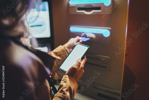 Quadro su tela Woman using street ATM machine to withdraw money inserting a credit card while s