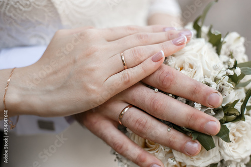hands of the bride and groom on a wedding bouquet