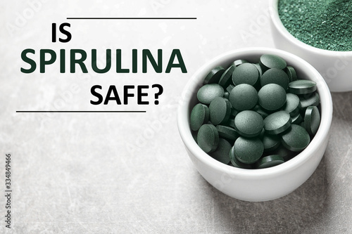 Bowls of spirulina pills and powder on grey background. Side effects