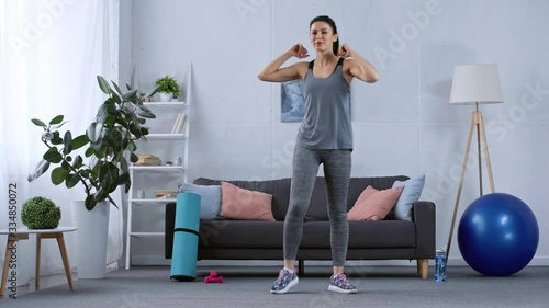 Smiling sportswoman training near sport equipment at home
