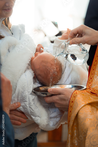 Infant baptism. Baptism ceremony in Church. Water is poured on the head of an infant. blessing with water