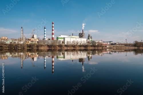 pipes of woodworking enterprise plant sawmill near river. Air pollution concept. Industrial landscape environmental pollution waste of thermal power plant