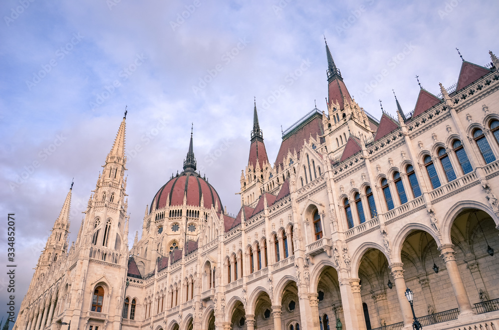 Building of the Hungarian Parliament Orszaghaz in Budapest, Hungary. The seat of the National Assembly. House built in neo-gothic style. Sunset light, pink and purple sky and clouds above