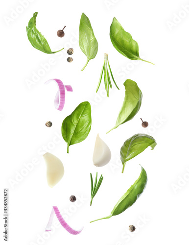 Basil leaves and other ingredients falling on white background
