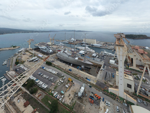Aerial view of sea dry dock in La Ciotat city, France, the cargo crane, boats on repair, a luxury sail yacht and motor yacht, mountain is on background, shipyard