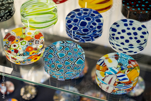 Decorative Murano glass pendants exposed in a glass case with reflection. Stained glass typical souvenir from the island of Murano, Venice, Italy