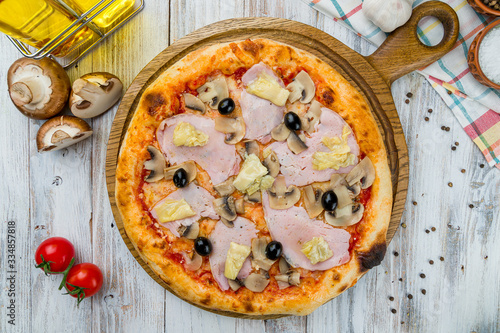 Capricciosa pizza with artichokes on white wooden table photo