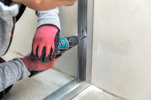 man fasten metal profile frame to the wall for draywall bulkhead photo