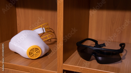 your choice about self isolation and responsibility in corona virus quarantine time domestic concept picture with medicine mask respirator and sunglasses on wooden cupboard shelf object