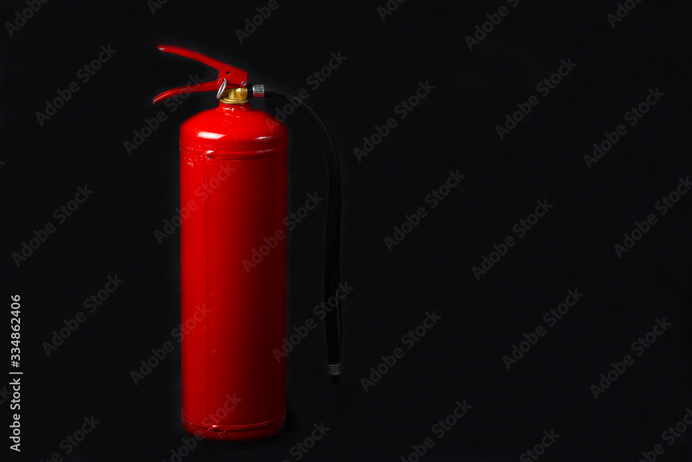 Red fire extinguisher on a black background.Fire equipment. Red fire extinguisher on a black background.Fire equipment.