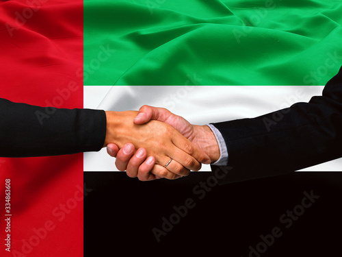 Business handshake on United Arab Emirates flag background 