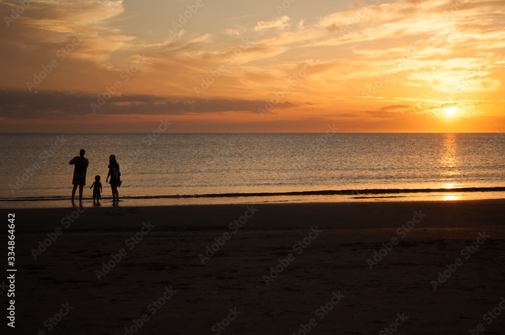 Family of three, mother, father and child, walking on the beach and looking at the sunset. Photo taken in Punta del Este, Uruguay.