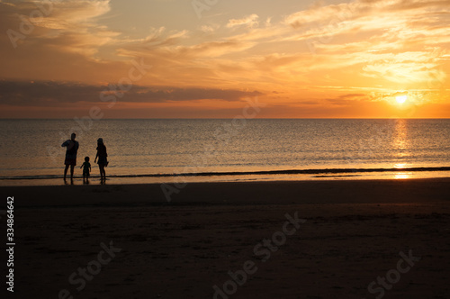 Family of three, mother, father and child, walking on the beach and looking at the sunset. Photo taken in Punta del Este, Uruguay.