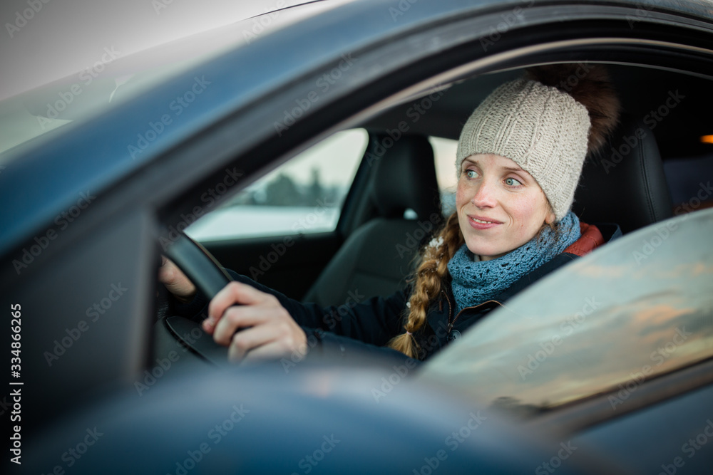 Woman driving a car - female driver at a wheel of a modern car, looking happy, smiling with a relaxed smile (shallow DOF; color toned image) Woman driving a car - female driver at a wheel of a modern car, looking happy, smiling with a relaxed smile (shallow DOF; color toned image)
