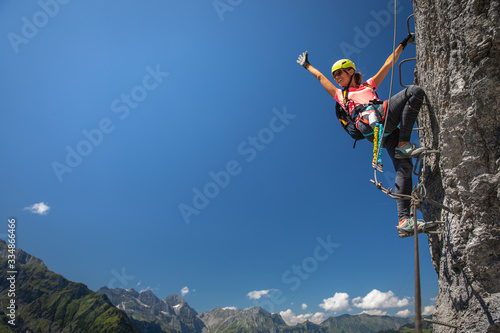 Pretty, female climber on a via ferrata - climbing on a rock in Swiss Alps photo