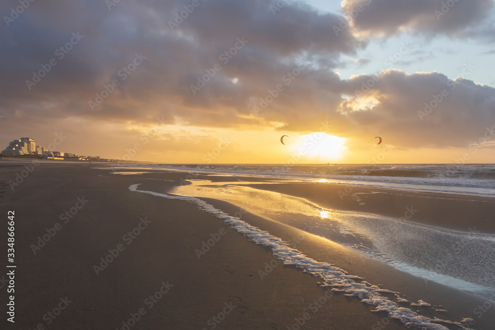View of the north sea beach on a windy winter day at sunset, people, kitesurfing. Noordwijk, the Netherlands