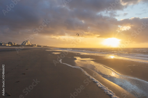 View of the north sea beach on a windy winter day at sunset  people  kitesurfing. Noordwijk  the Netherlands