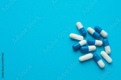 Antiviral capsules, pills for treatment on a blue background. White-blue capsules. Flat lay, top view