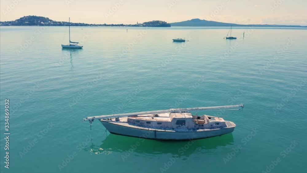 Aerial: Abandoned boat floating on the water. Auckland, New Zealand Aerial: Abandoned boat floating on the water. Auckland, New Zealand