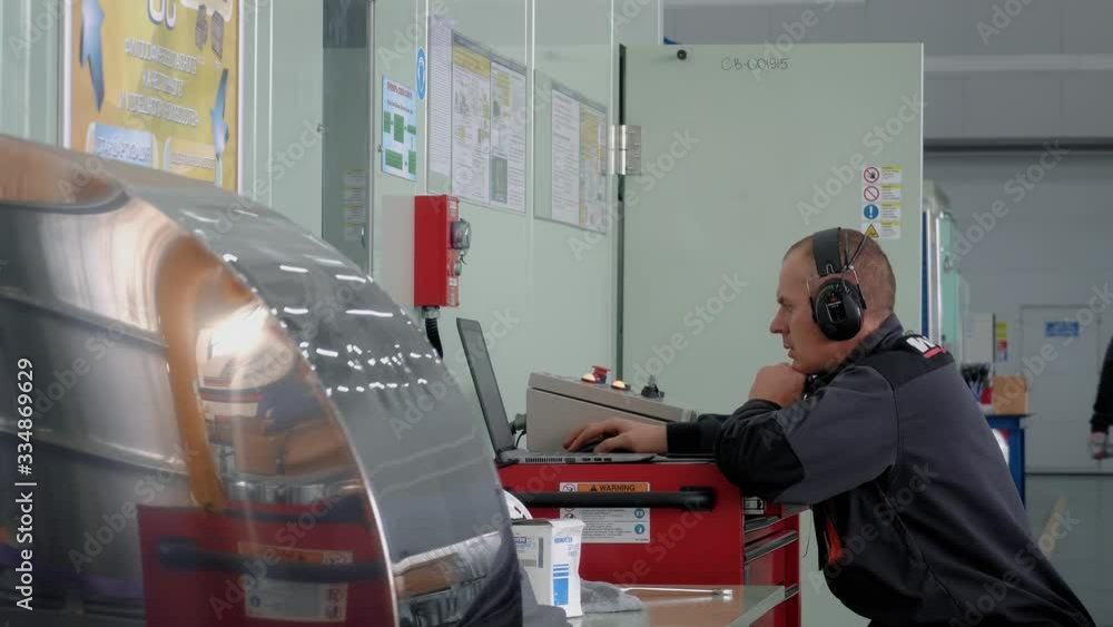 European man, the mechanic of the engine restoration factory makes a test engine start. He listens carefully to the sound of the old engine. European man, the mechanic of the engine restoration factory makes a test engine start. He listens carefully to the sound of the old engine.