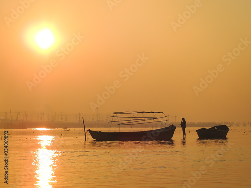 Sunrise at ganges river with lonely boatman on the main day of the Kumbh Mela festival in Allahabad, Uttar Pradesh, India. photo