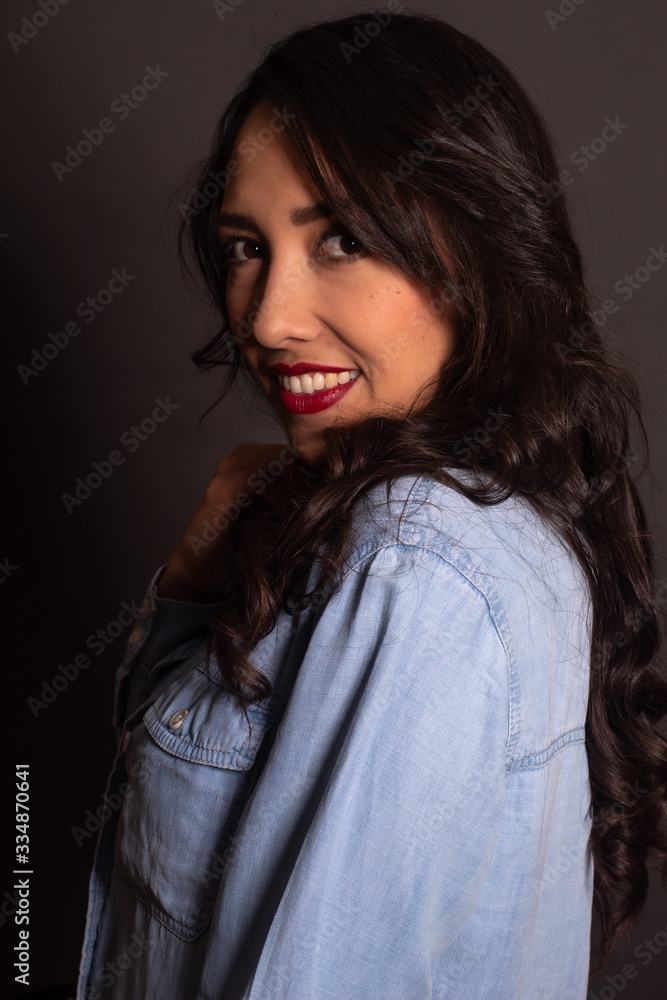 Retrato de mujer casual mexicana alegre posando en fondo gris blusa de mezclilla Retrato de mujer casual mexicana alegre posando en fondo gris blusa de mezclilla