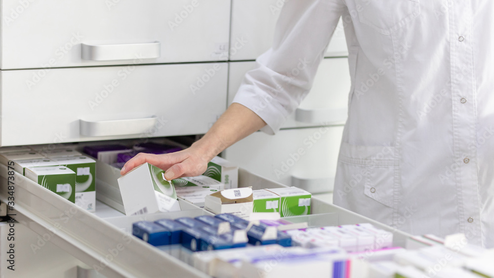 Pharmacist holding medicine box and capsule pack in pharmacy drugstore. Pharmacist holding medicine box and capsule pack in pharmacy drugstore.