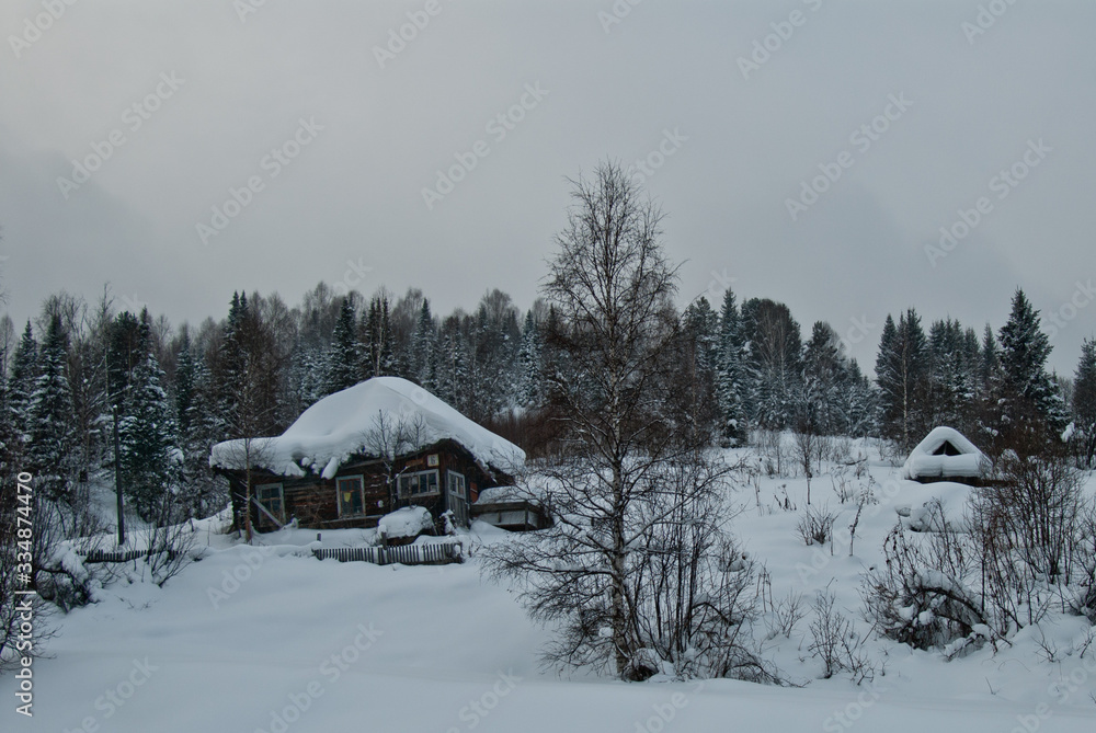 Wooden house in the winter with the smoke from the chimney