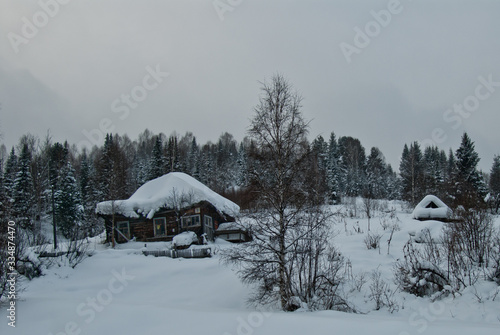 Wooden house in the winter with the smoke from the chimney