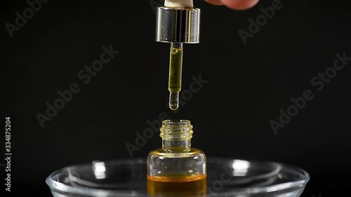 Aromatic oil in a light glass bottle on a dark background. Drops. Creating spirits. Spa treatments.