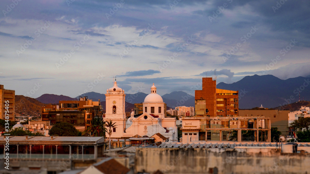 Amazing view of the city of Santa Marta, Colombia. Colonial city with church view during the sunset, warm colors, beautiful sky and mountains.