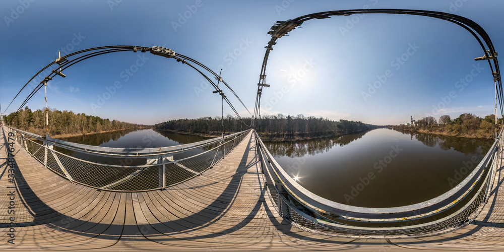 Fototapeta premium pełna bezszwowa sferyczna panorama hdri 360 stopni widok na drewniany most wiszący dla pieszych nad szeroką rzeką w słoneczny dzień w rzucie równokątnym. skybox dla treści VR AR