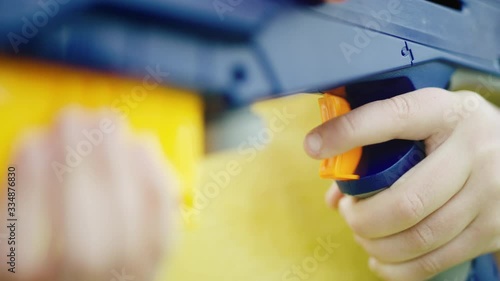 Close on young boy's finger as he pulls trigger on large colorful toy gun photo