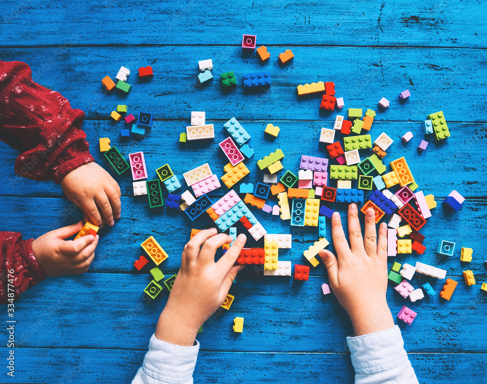 Children play and build with colorful toy bricks, plastic blocks.